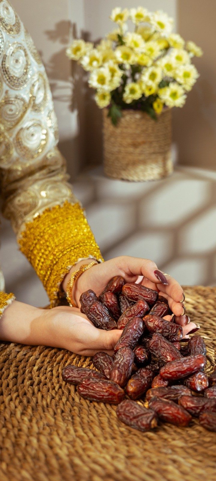 Hands holding Piarom dates on a woven palm mat
